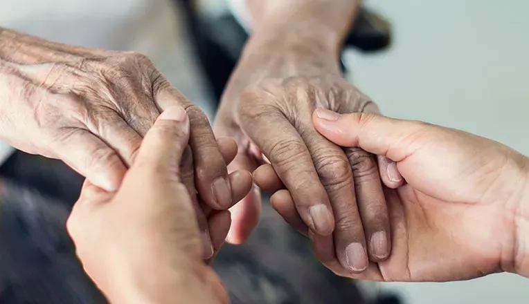 Mains d'une personne tenant chaleureusement celles d'une personne âgée.