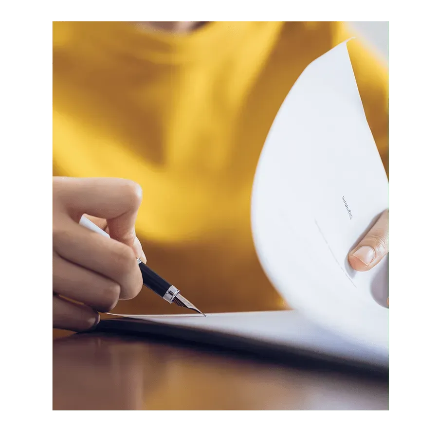 Personne signant un document officiel avec un stylo-plume.
